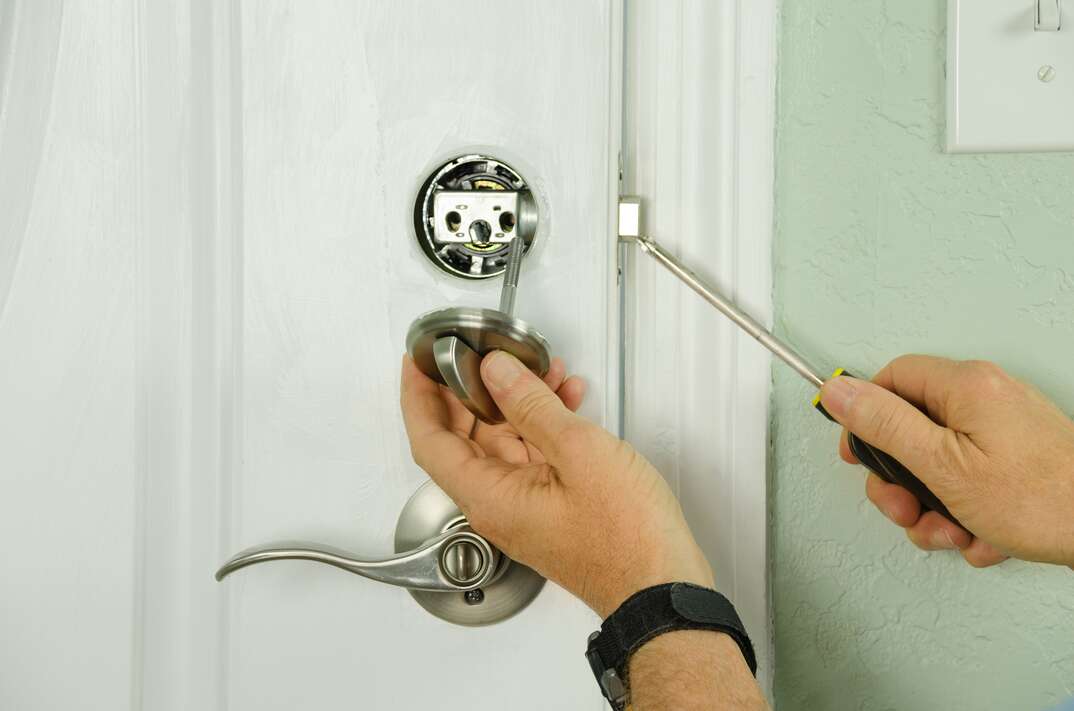 A worker is replacing a home s dead bolt lock