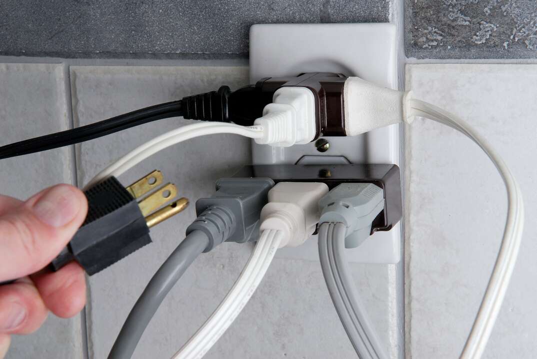 Overloaded Electrical outlet with no room for more plugs, overloaded electrical outlet, electrical outlet, outlet, electrical, electric, electricity, overloaded, outlet, plugged in, plug, plugged, plug in, hand, human hand, danger, safety, wall outlet, tile