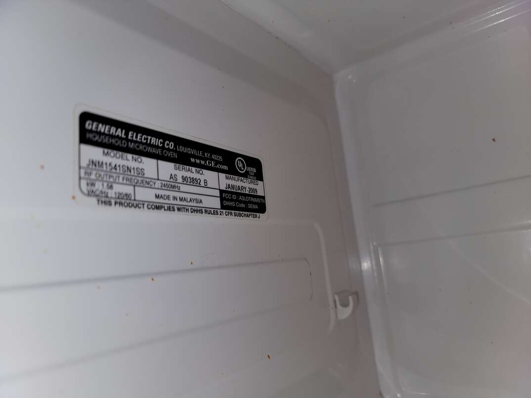 Open door of microwave reveals interior of appliance as well as the tag where you can find the serial number and model number.