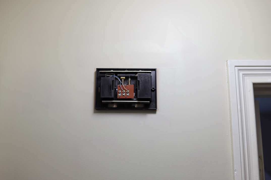 An image of the inside of a broken doorbell panel on a wall in a home