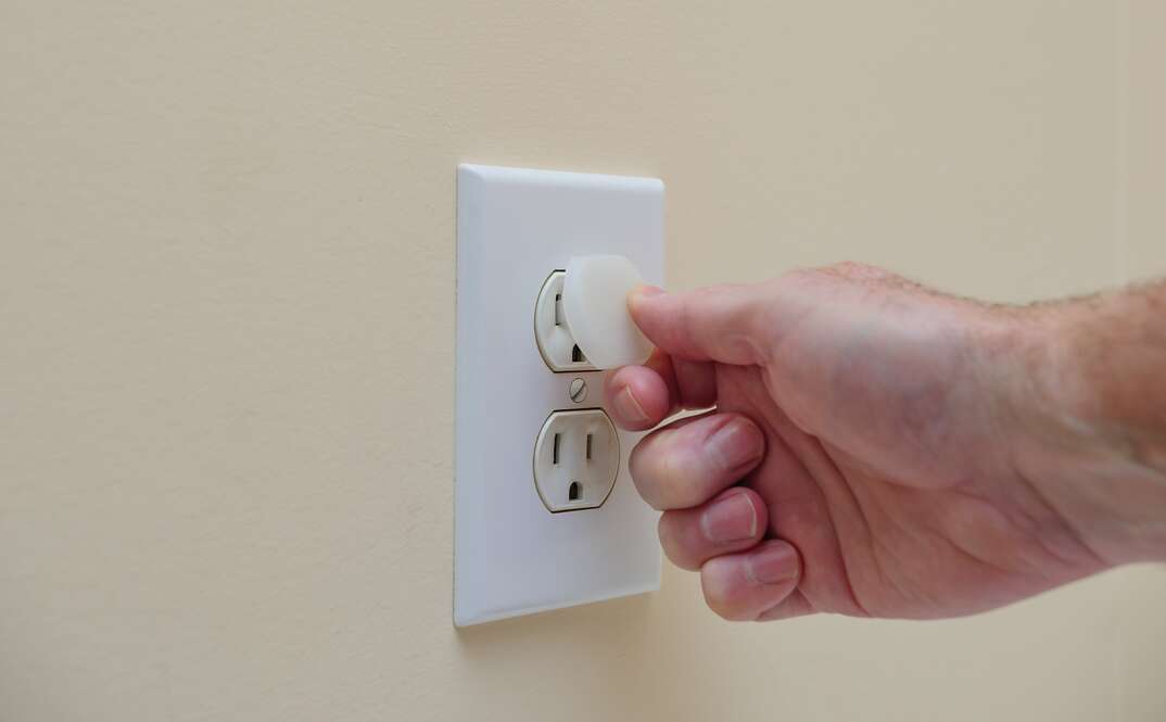 Installing electrical outlet electricity safety cover to prevent child electrocution, plastic plugs, plastic covers, outlet covers, outlet, electrical outlet, electrical, electricity, electric, shock, electrocution, safety, electrical safety, plug in, hand, human hand, child proofing, baby proofing