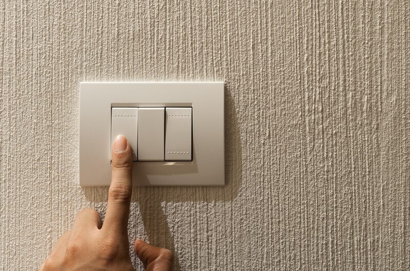 Closeup of A finger is turning on a lighting switch on concrete texture wall background with copyspce.