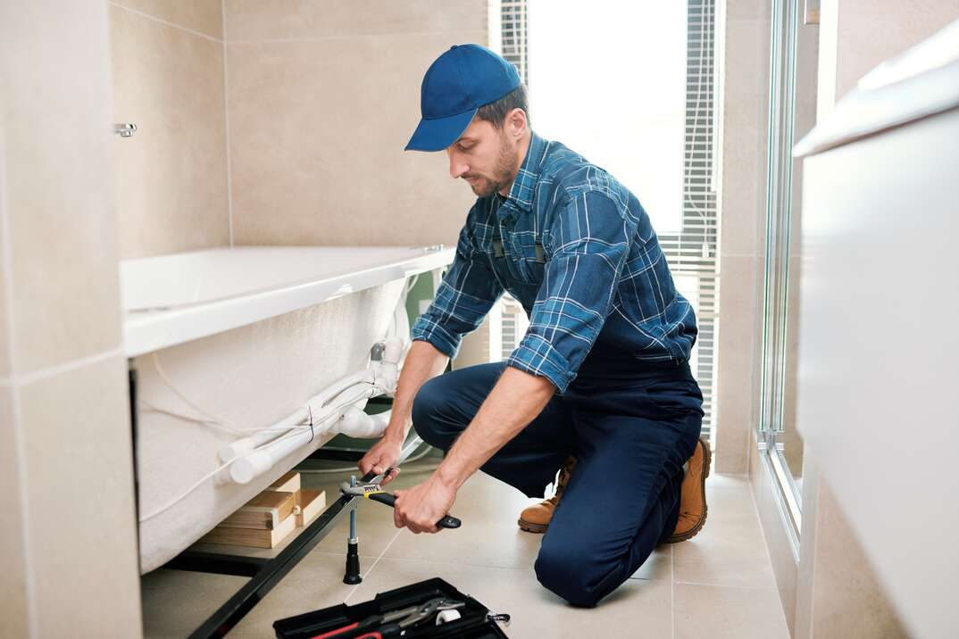 a male technician preparing to level a newly installed bathtub 