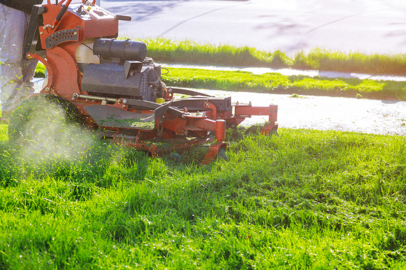 Man worker cutting grass in summer with a professional gardener mowing lawn