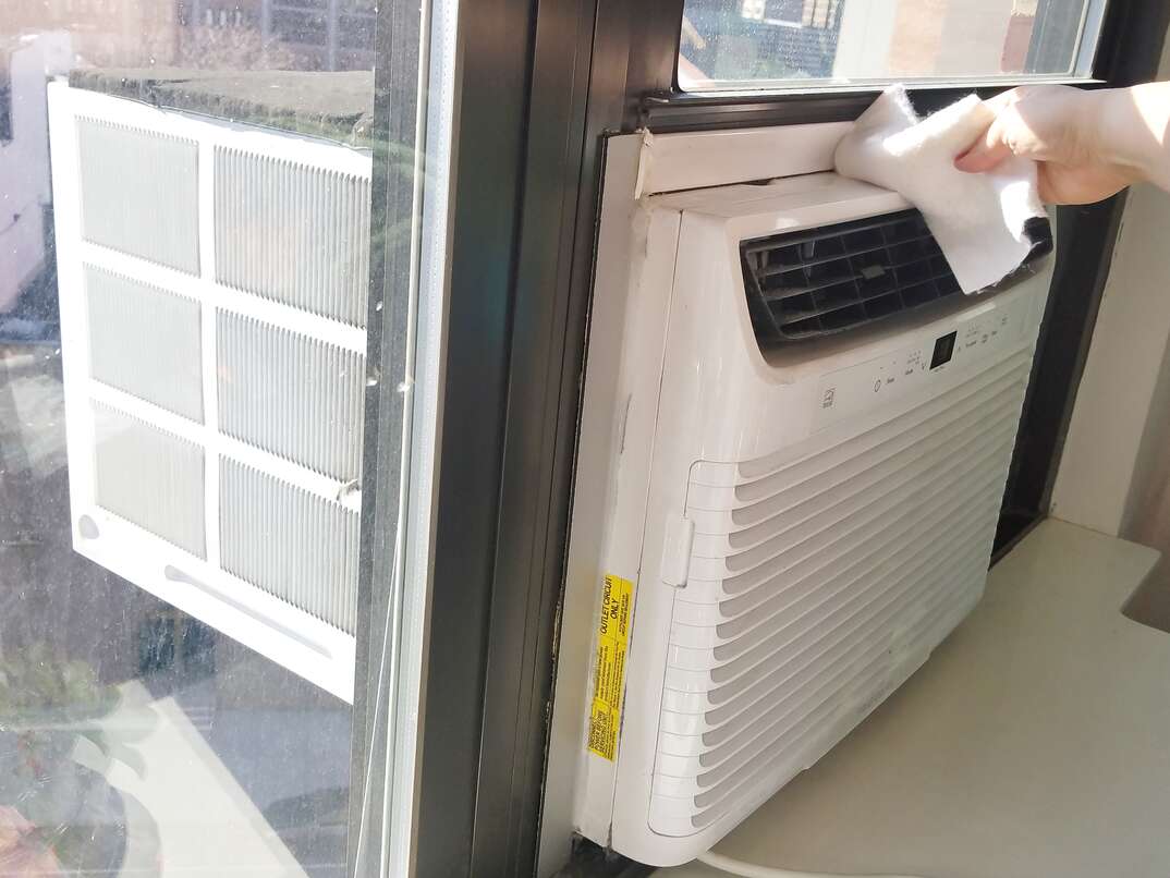 White window-unit air conditioner being wiped clean 
