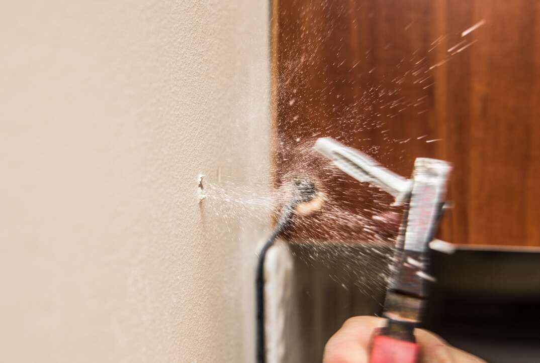 Close up view of person hand removing old plastic dowel, nylon wall plug from drywall with pliers at home. Home renovations concept.