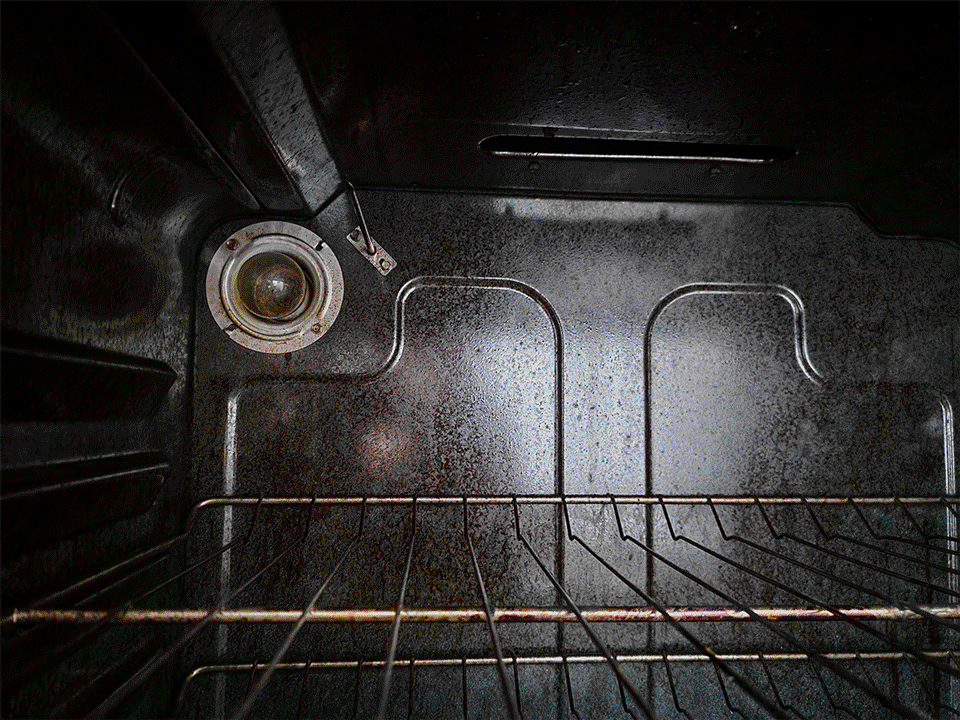 inside of a dark residential oven as the internal light bulb flickers