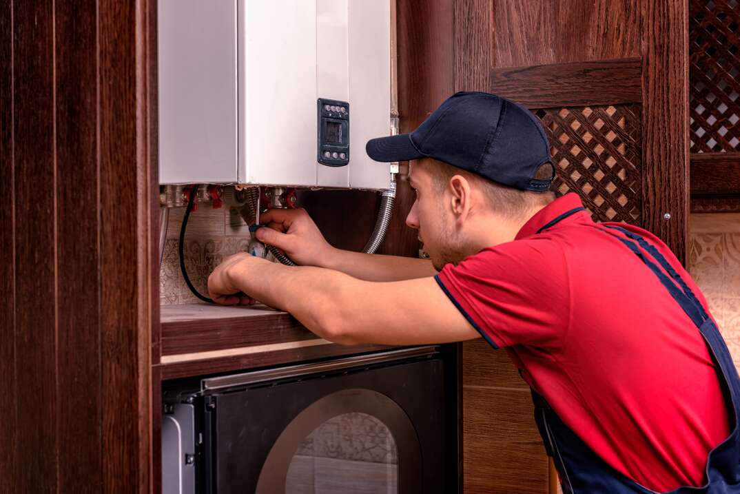 Plumber adjusts gas boiler before operating.