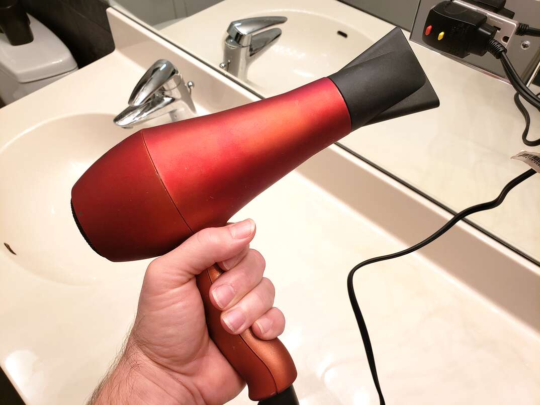 man holding red hair dryer in bathroom