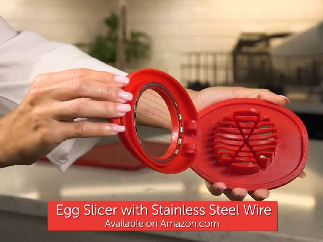 female hands holding up a red egg slicer