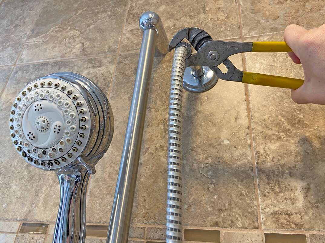 close up image of a new shower head being installed in place of an existing fixture 