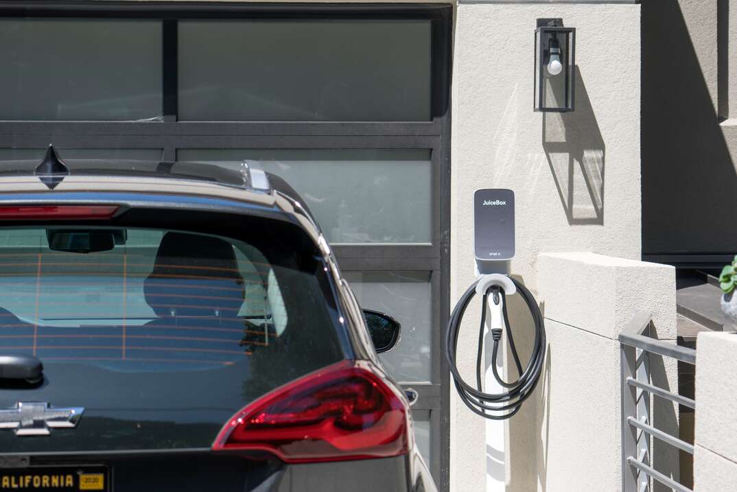 a residential home showing a Juicebox EV car charger mounted to a wall near where a chevy ev is parked