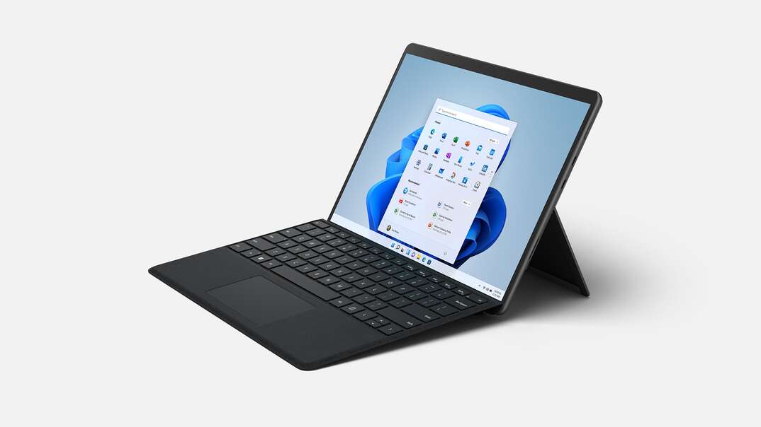 A black colored Microsoft Surface tablet laptop hybrid sits with its screen open sitting against a white background