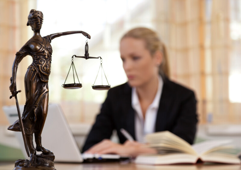 Eine junge Rechtsanwältin sitzt an ihrem Schreibtisch im Büro