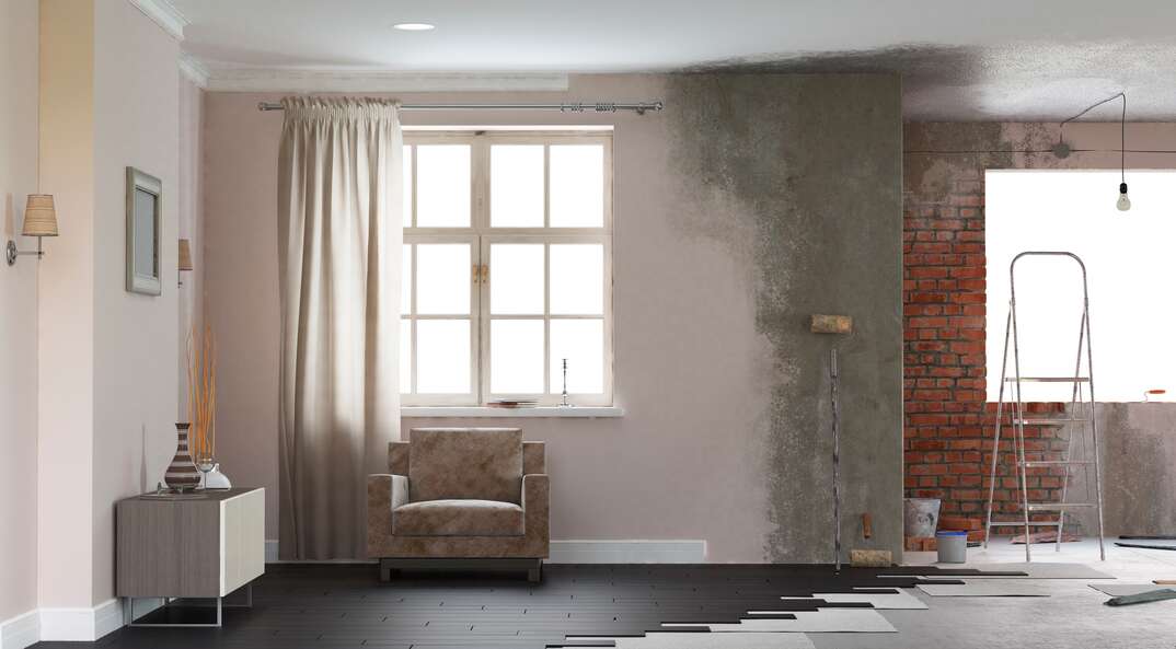 A home undergoing renovation is shown with one side of the room torn up due to the work being done while the other side remains intact and livable, renovation, home renovation, windows, natural light, flooring, missing floorboards, ladder