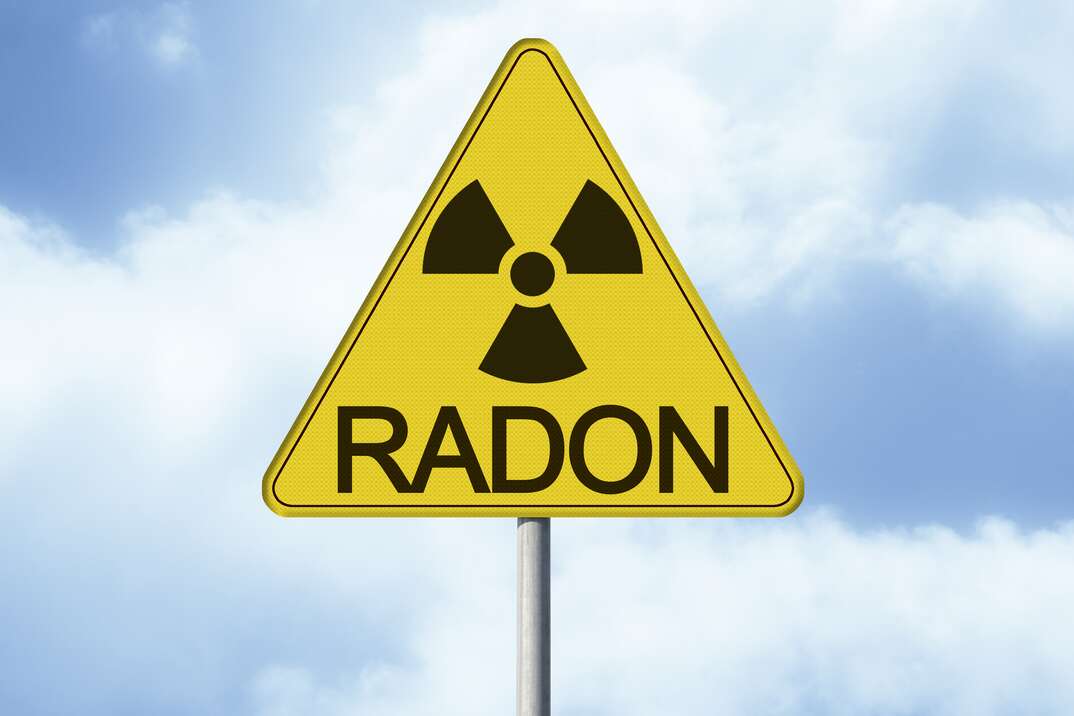 Danger of radioactive contamination from RADON GAS - concept with warning symbol of radioactivity on road sign - image with copy space.