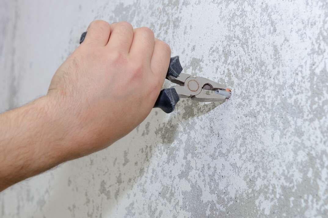 worker with pliers pulls the plug out of the wall