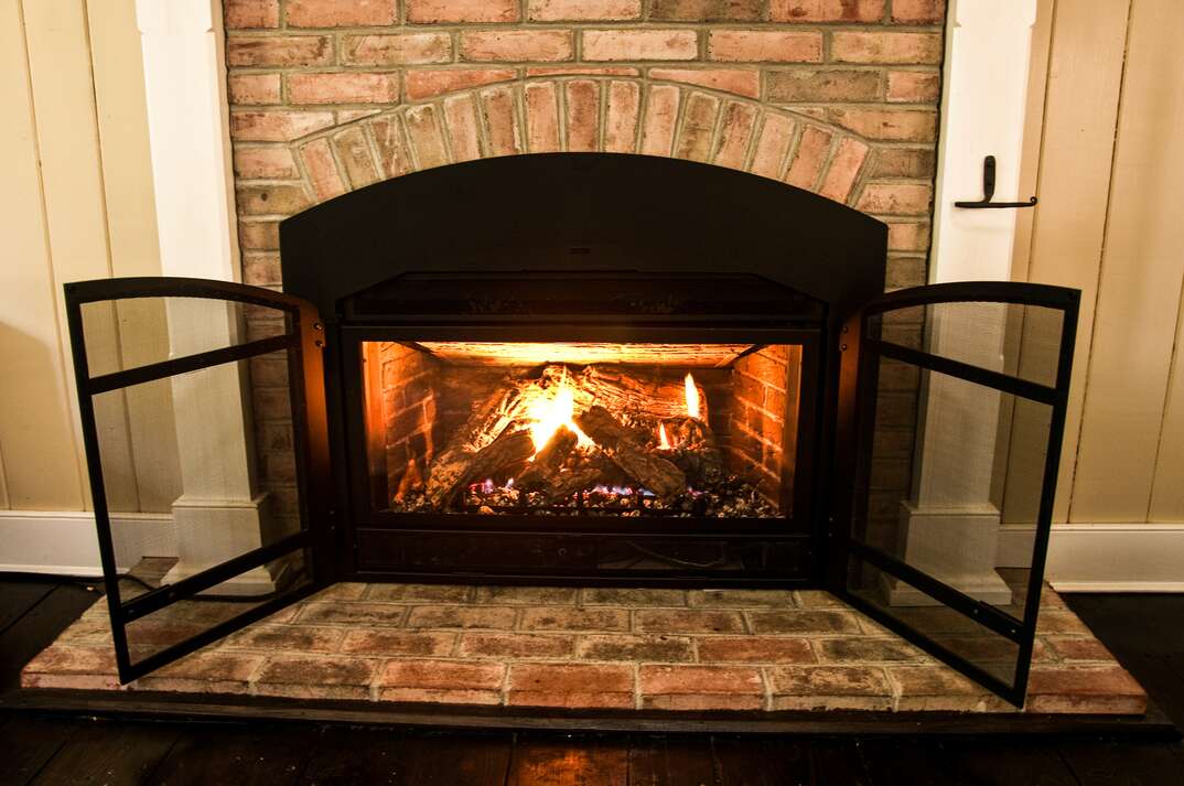 Natural gas fireplace with protective screen and surrounded by brick