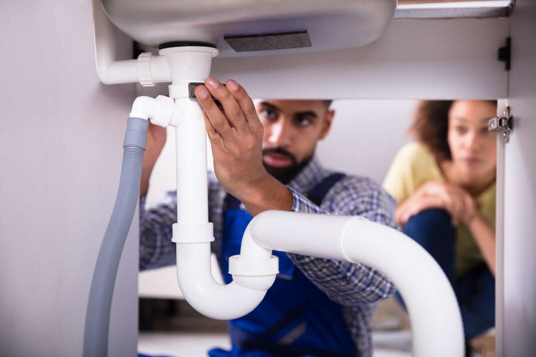 close up of male plumber fixing a sink in the kitchen