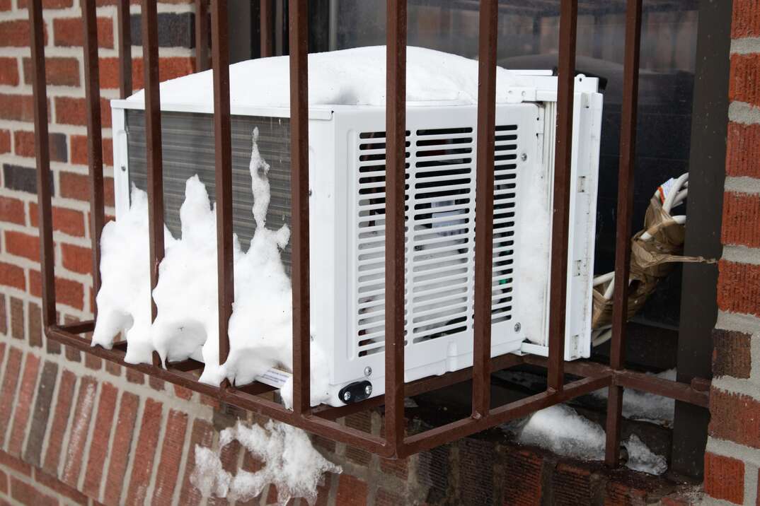 Window Air Conditioner in a Barred Cage with Snow in New York City during the Winter