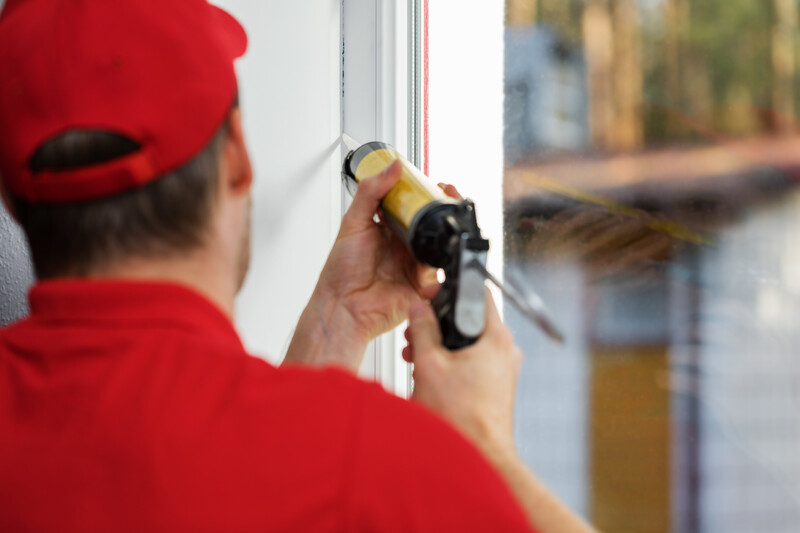 worker applying caulk around window frame