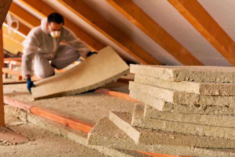 Man installing thermal insulation layer under the roof - using mineral wool panels