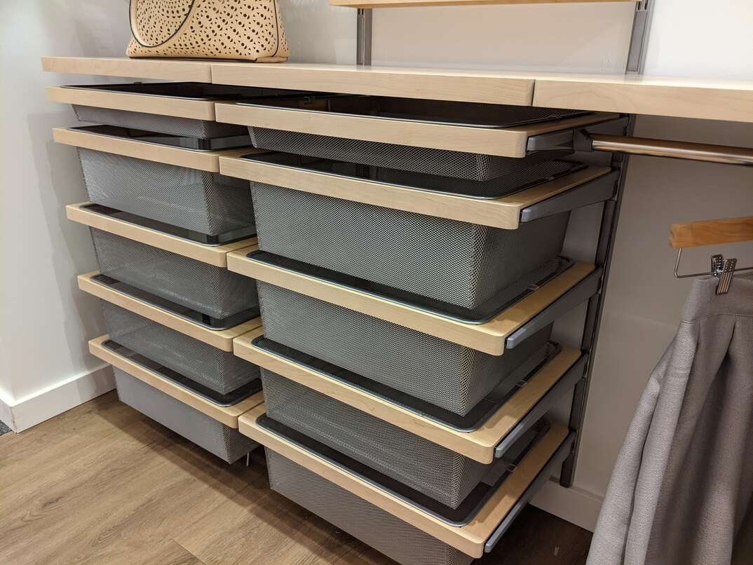 Angled view of a set of wire mesh drawers inside a large walk in closet