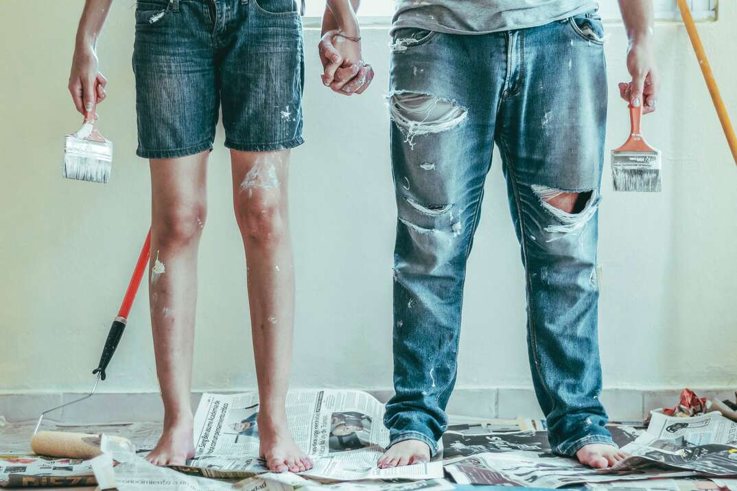 bottom half pictured of couple holding hands while painting a room