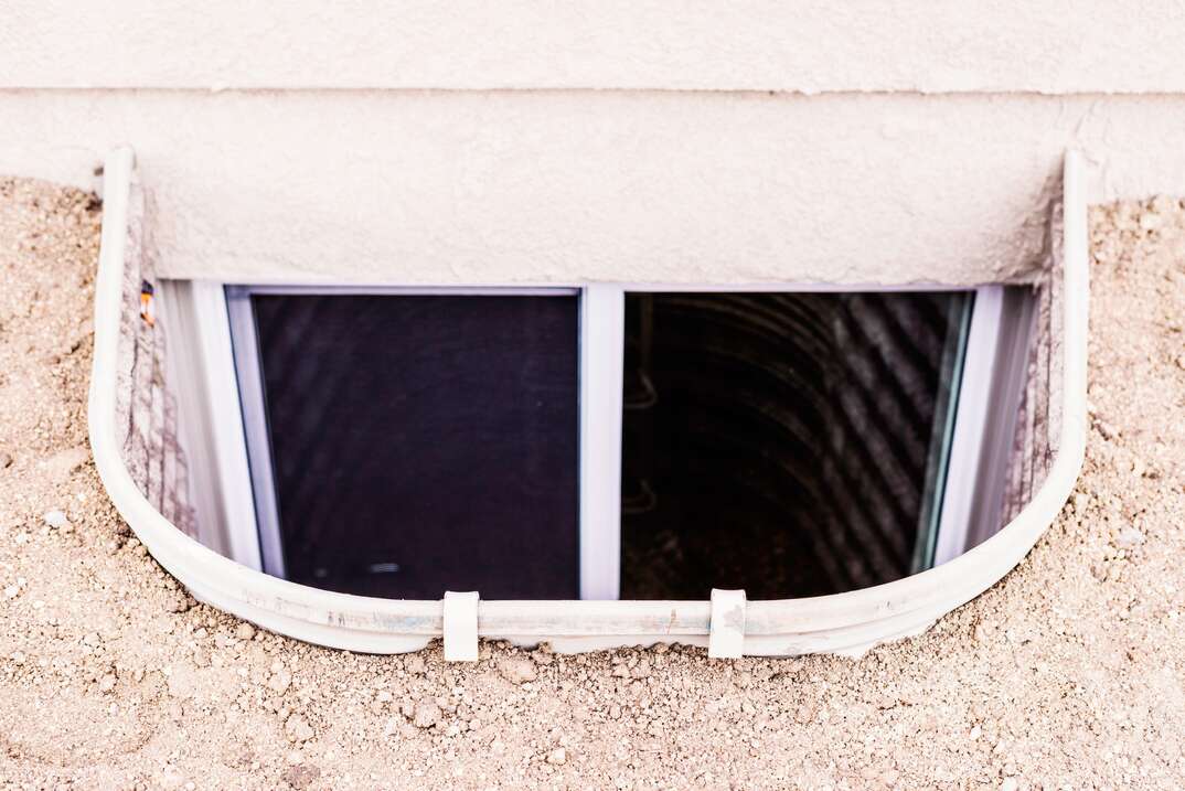 Uncovered window well with escape ladder from basement bedroom  Safety