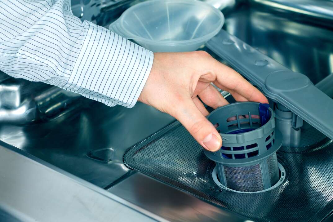 Man s hand taking out a dishwasher filter