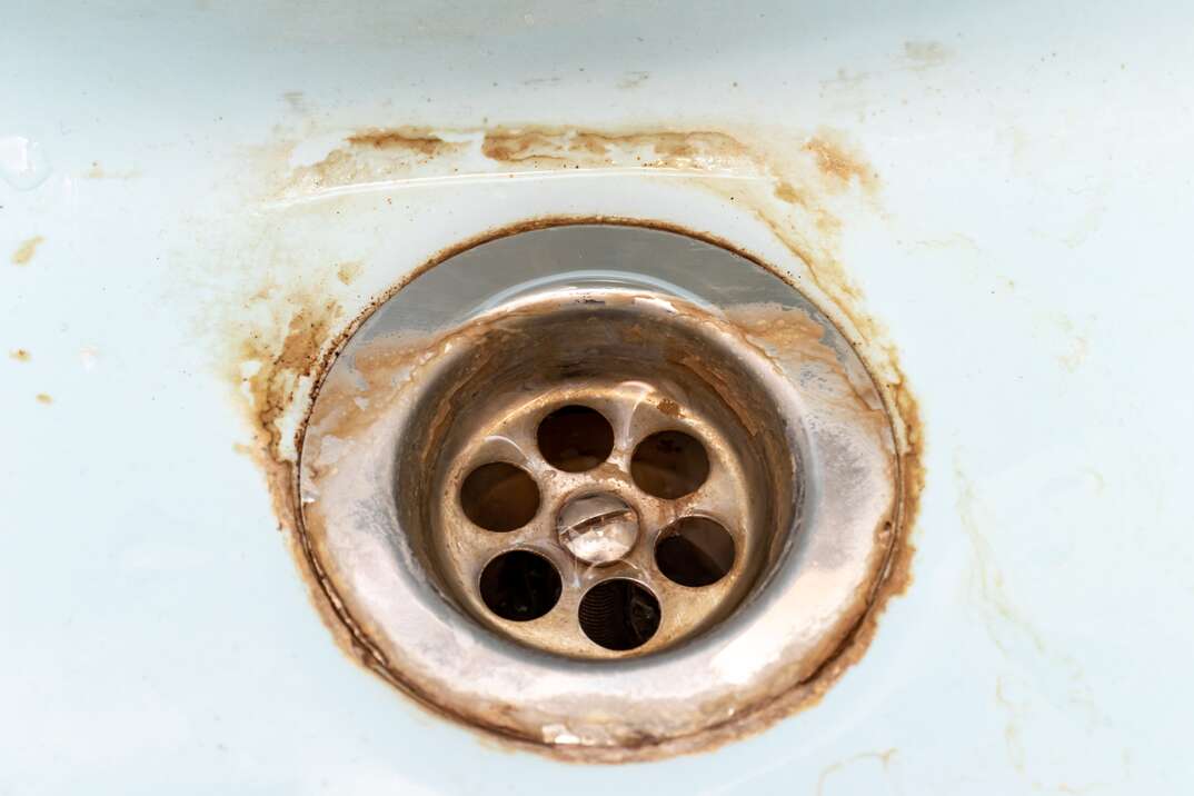 Dirty sink drain mesh, dirty rusty bathroom washbowl, hole with limescale or lime scale and rust on it close up