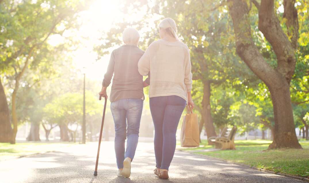 Walking, park and and woman with elderly mother for bonding, assistance and help outdoors. Nature, family and female person with disability with cane and adult daughter for wellness, relax or support.