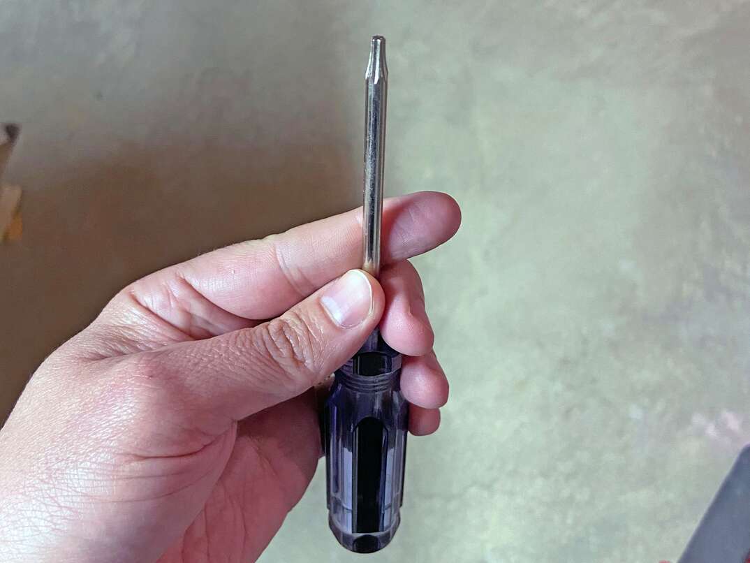 hand holding up a torx or star-bit screw driver