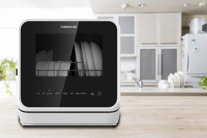 Photo of a  faberware  branded countertop dishwasher sitting on a modern countertop with a white modern kitchen in the background  This image is media supplied 