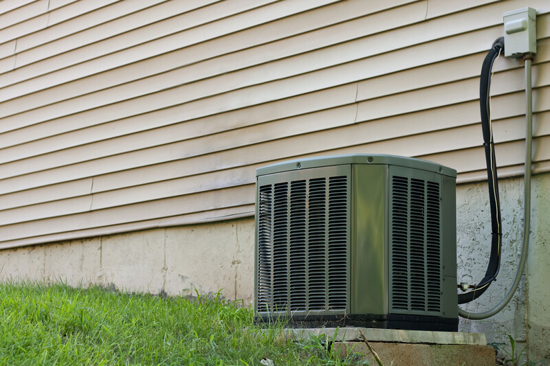 A residential central air conditioning unit sitting outside a home used for regulating the homes AC to a comfortable level.