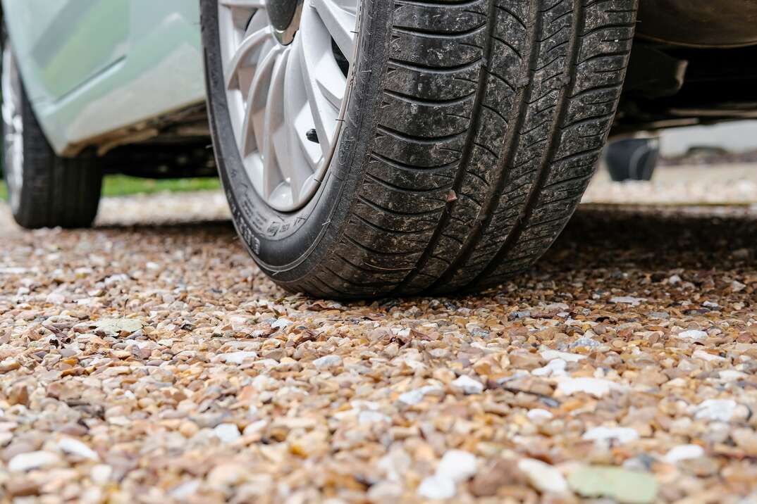 close up of a vehicle s tire parked on a gravel driveway