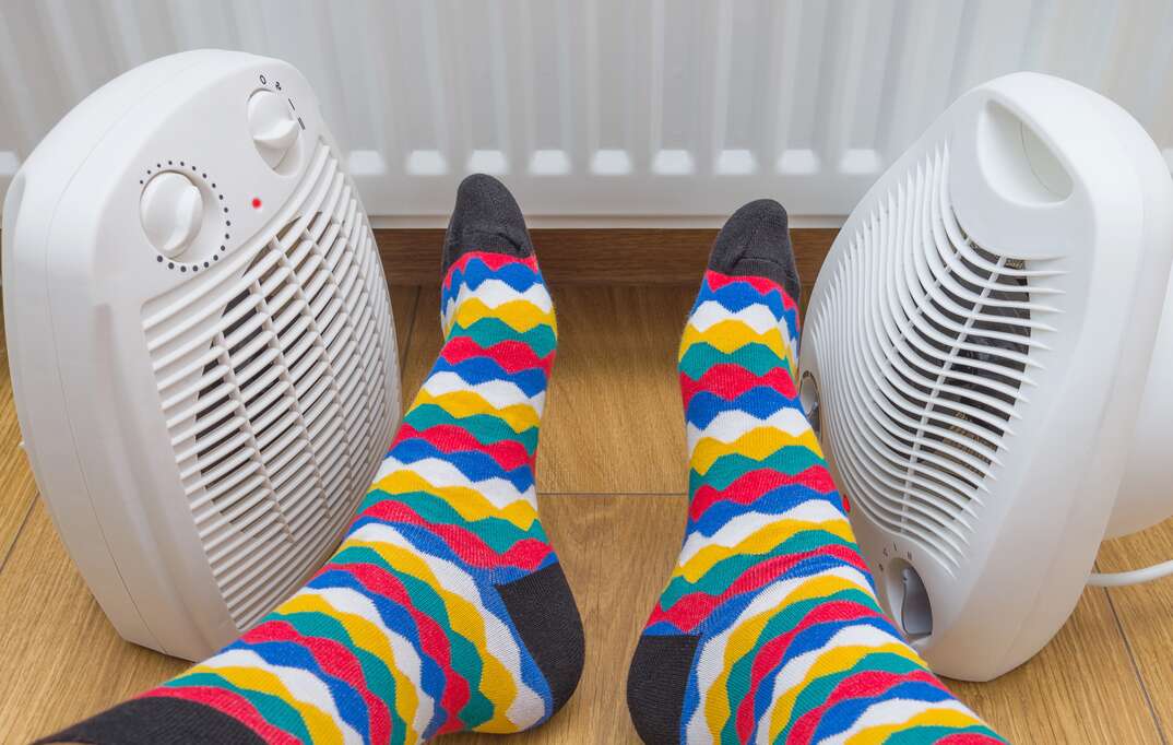 A pair of household space heaters warming a pair of feet