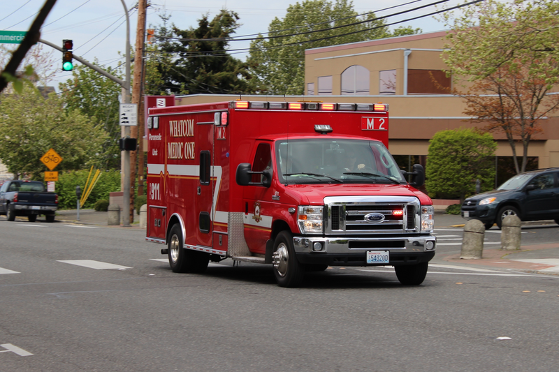 A red ambulance drive on a city street during the day, ambulance, medical emergency, medical, emergency vehicle, driving, emergency